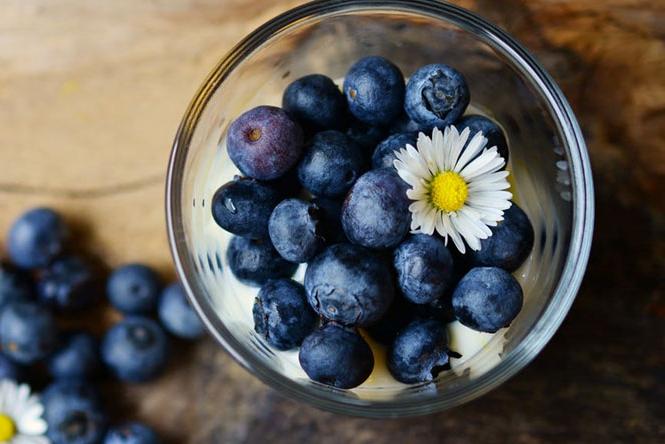 a glass bowl full of blueberries and a flower